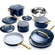 an assortment of blue pots and pans on a white surface with gold handles,