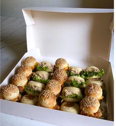 a box filled with mini sandwiches covered in sesame seeds