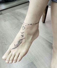 a woman's foot with a tattoo on the ankle and an arrow in the shape of a heart