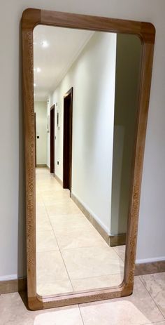 a large mirror sitting on the floor in front of a white wall and tiled floor