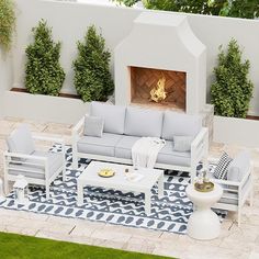 an outdoor living room with white furniture and a fireplace