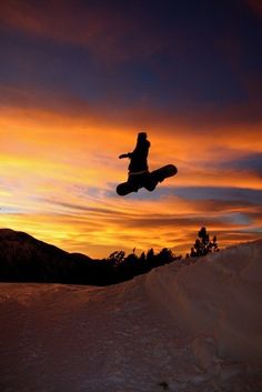 a snowboarder is in the air at sunset