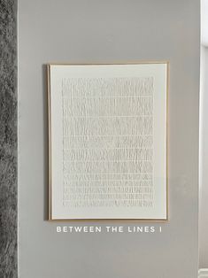 a white framed art piece hanging on the side of a wall with words between the lines iv