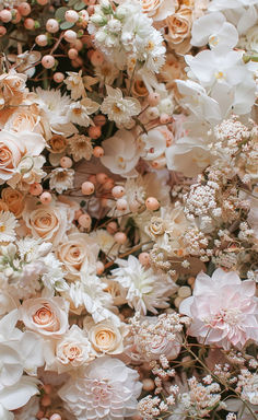 a bunch of flowers that are all over the place in front of a wall with white and pink flowers on it