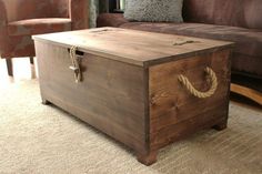 a wooden box sitting on top of a carpeted floor next to a brown couch