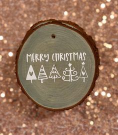 a christmas ornament on top of a piece of wood that says merry christmas