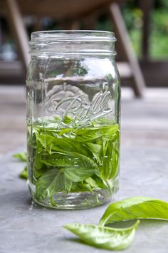 a jar filled with green leaves sitting on top of a table