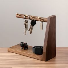 a wooden stand holding keys and two small black dogs on it's sides, with one key holder attached to the other