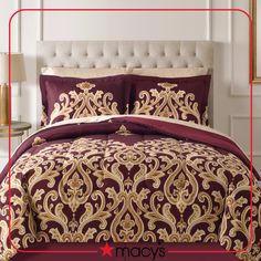 a bed covered in a maroon and gold comforter