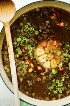 a pot filled with soup and vegetables next to a wooden spoon