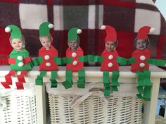 some paper elfs are sitting in front of a basket on a table with red and green decorations