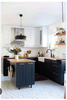 a kitchen with black and white cabinets, an island in the middle and shelves above it