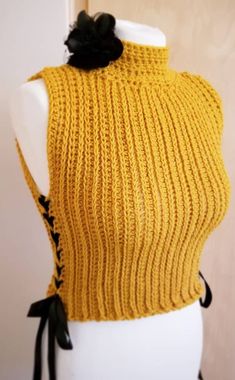 a mannequin wearing a yellow knitted sweater with a black flower on it