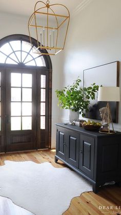 a living room with a black cabinet and white rug in front of the door that leads to an arched window