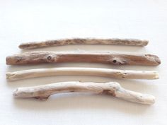 three pieces of driftwood sitting on top of a white cloth covered table next to each other