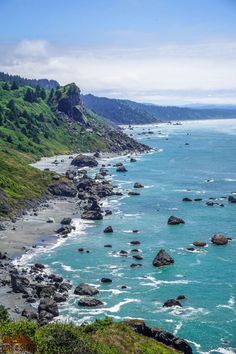 the coast line is lined with rocks and green hills on either side, as well as blue water