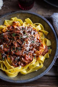 pasta with meat sauce and parmesan cheese in a bowl on a wooden table