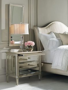 a white bed sitting next to a silver dresser with flowers on it's side