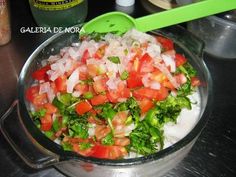 a pot filled with vegetables and onions on top of a stove next to a green spatula