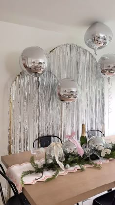 the table is set with silver balloons and greenery