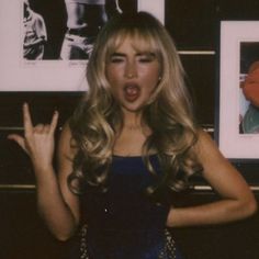 a woman with long blonde hair making a face and holding her hands up in front of her mouth