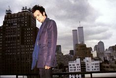 a man standing on top of a roof in front of a cityscape with tall buildings