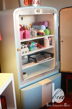 an old fashioned refrigerator with the door open and shelves full of crafting supplies on it