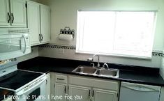 a kitchen with white cabinets and black counter tops is pictured in this image, there is a window over the sink