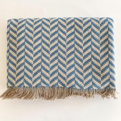 a blue and white blanket with fringes on the bottom, sitting on top of a table