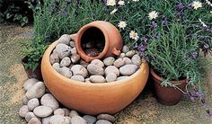 a potted planter filled with lots of rocks and flowers next to some plants