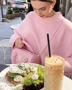 a woman sitting at a table with a plate of food and drink in front of her