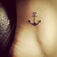 a small anchor tattoo on the side of a woman's leg, with a heart