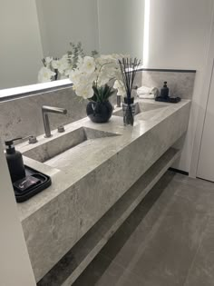 a bathroom counter with two sinks and flowers in vases on the counter top next to it