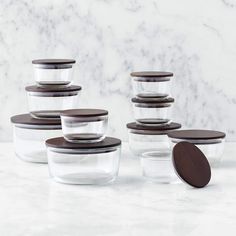 glass containers with wooden lids are stacked on a marble countertop next to each other