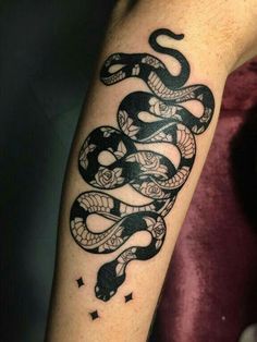 a black and white snake tattoo on the right arm, with stars around its neck