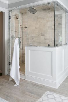 a bathroom with a walk in shower next to a white bath tub and wooden floors