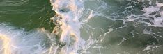 an aerial view of the ocean with waves crashing on top of each other and one person standing in the water