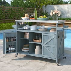 an outdoor kitchen cart with food and drinks on it in front of a swimming pool