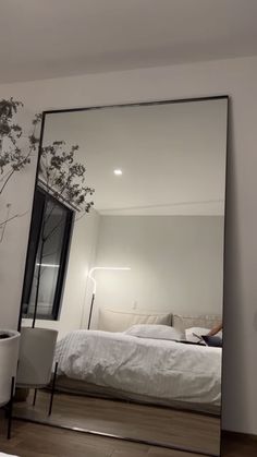 a bedroom with a large mirror on the wall next to a bed and potted plant