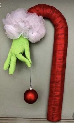 a green hand hanging from the side of a wall next to a red christmas ornament