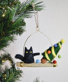 an ornament hanging from a christmas tree with a black cat and small toy