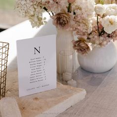 a table topped with vases filled with flowers next to a sign that says n