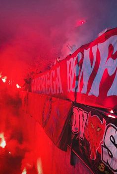 red and black fire is lit up in the sky behind a wall with graffiti on it