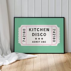 a green framed sign sitting on top of a wooden floor next to a white curtain