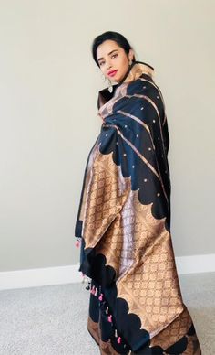 This stunning black 100% Mulberry Katan silk saree is handwoven in Banaras, known for its intricate designs and high-quality craftsmanship. The saree features a beautiful shade of black body and Meenadar flowers on the body with golden zari work, creating a mesmerizing effect. The body and palla has the kadbaan design depicting the pillars and corridors of the old historical palaces . The saree is perfect for any special occasion, such as a wedding, festival, or formal event. Comes finished with Black Art Silk Anarkali Saree, Black Semi-stitched Traditional Wear For Ceremonial, Black Art Silk Anarkali Dupatta, Black Art Silk Dupatta For Anarkali, Black Semi-stitched Dupatta In Traditional Drape, Black Silk Saree For Eid, Black Semi-stitched Dupatta, Black Tussar Silk Dupatta With Traditional Drape, Black Unstitched Silk Dupatta