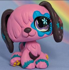 a pink toy dog sitting on top of a blue floor next to a rainbow colored wall