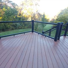 a wooden deck with black railing and handrails in front of a grassy area