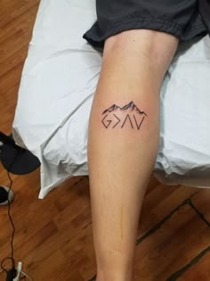 a person with a tattoo on their leg sitting on a bed next to a pillow