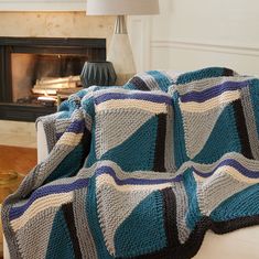 a blue and white blanket sitting on top of a couch next to a fire place