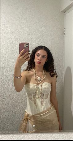 a woman in a corset taking a selfie with her cell phone while wearing pearls